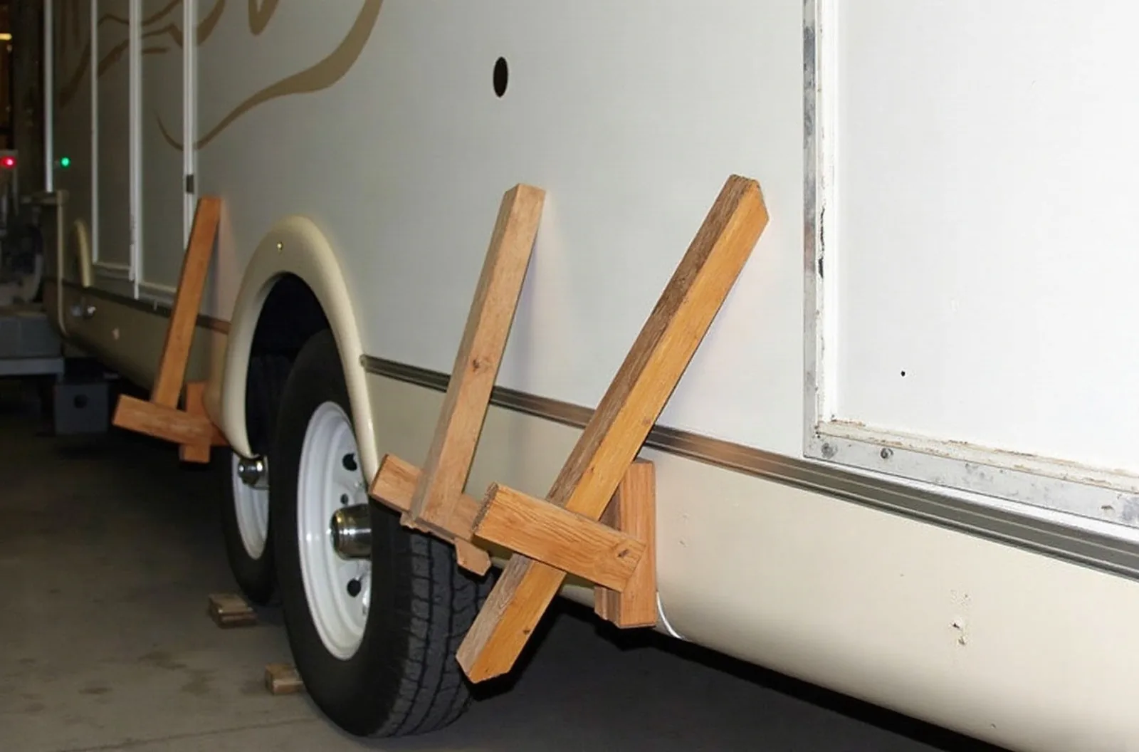 Wooden braces and clamps hold a section of white fiberglass RV sidewall flat during delamination repair outside a shop.